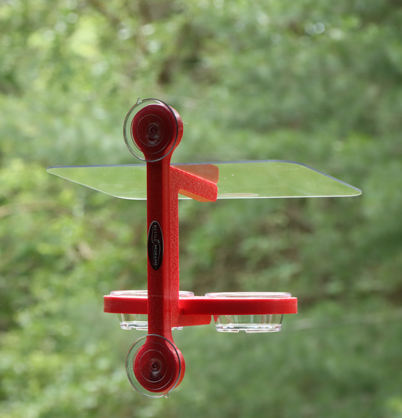 Red recycled plastic bird feeder is window mounted with suction cups. Holds two clear plastic cups. Clear roof. 