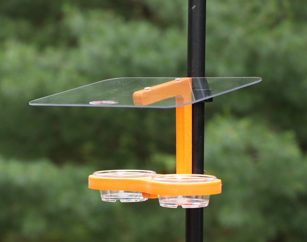 Orange recycled oriole feeder is pole mounted with two vinyl-coated clips. Holds two removable clear plastic dishes. Has a large clear roof.