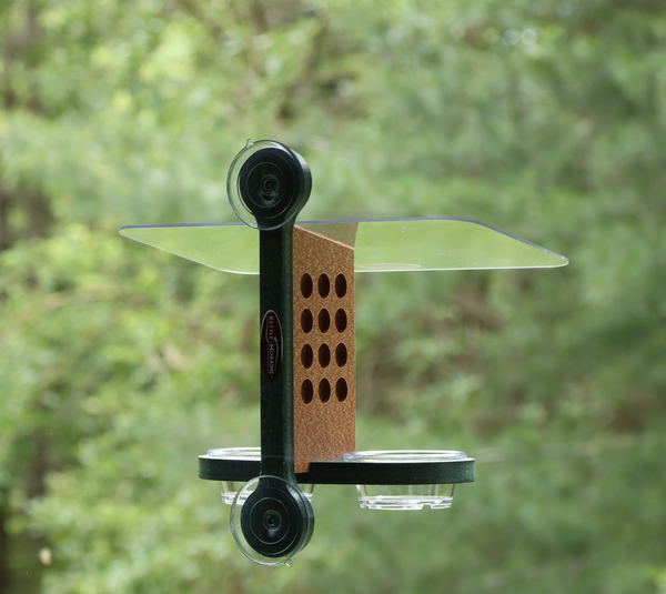 Recycled plastic window mount feeder with 2 suction cups and green mounting bracket. Has 12 holes on both sides of brown body, a clear acrylic roof, and green base holds 2 clear cups. 