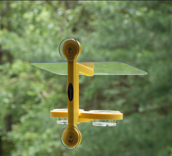 Yellow recycled plastic bird feeder is window mounted with suction cups. Holds two clear plastic cups. Clear roof. 