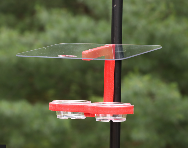 Red bird feeder is pole mounted with two clips. Holds two clear removable plastic cups. Large clear roof. 