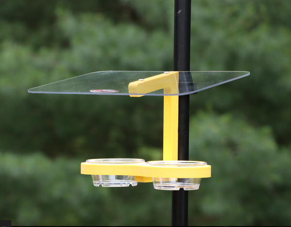 Yellow bird feeder is pole mounted with two clips. Holds two clear removable plastic cups. Large clear roof. 