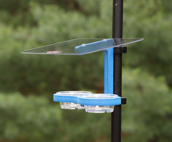 Blue bird feeder is pole mounted with two clips. Holds two clear removable plastic cups. Large clear roof. 