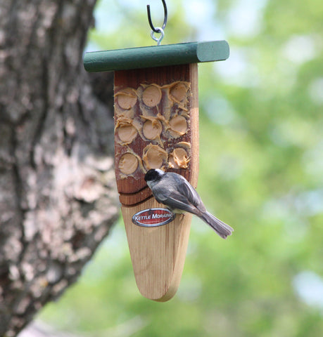 chickadee eating peanut butter on cedar feeder on tree
